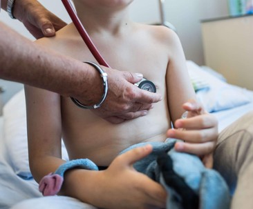 Lekarka osłuchuje klatkę piersiową kilkuletniego chłopca