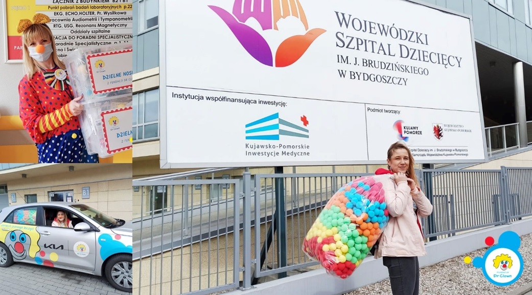 Pani klaun z darami dla dzieci przed Wojewódzkim Szpitalem Dziecięcym w Bydgoszczy, promująca radość i wsparcie.