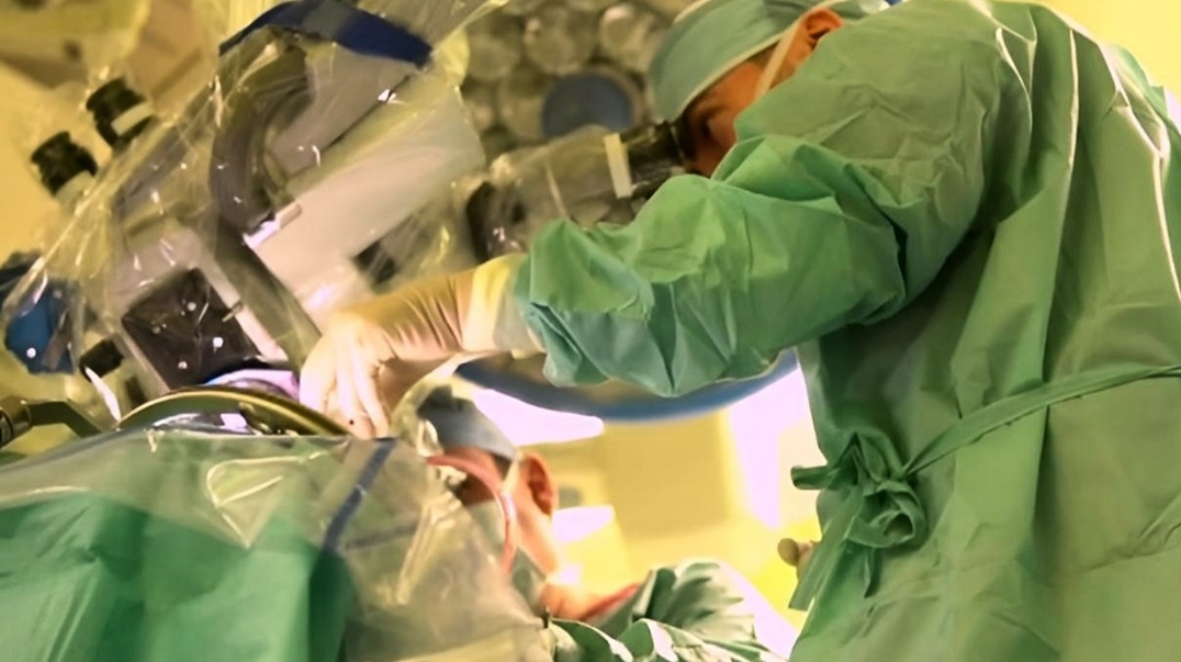 Chirurg przeprowadza skomplikowaną operację z wykorzystaniem mikroskopu chirurgicznego w sali operacyjnej.