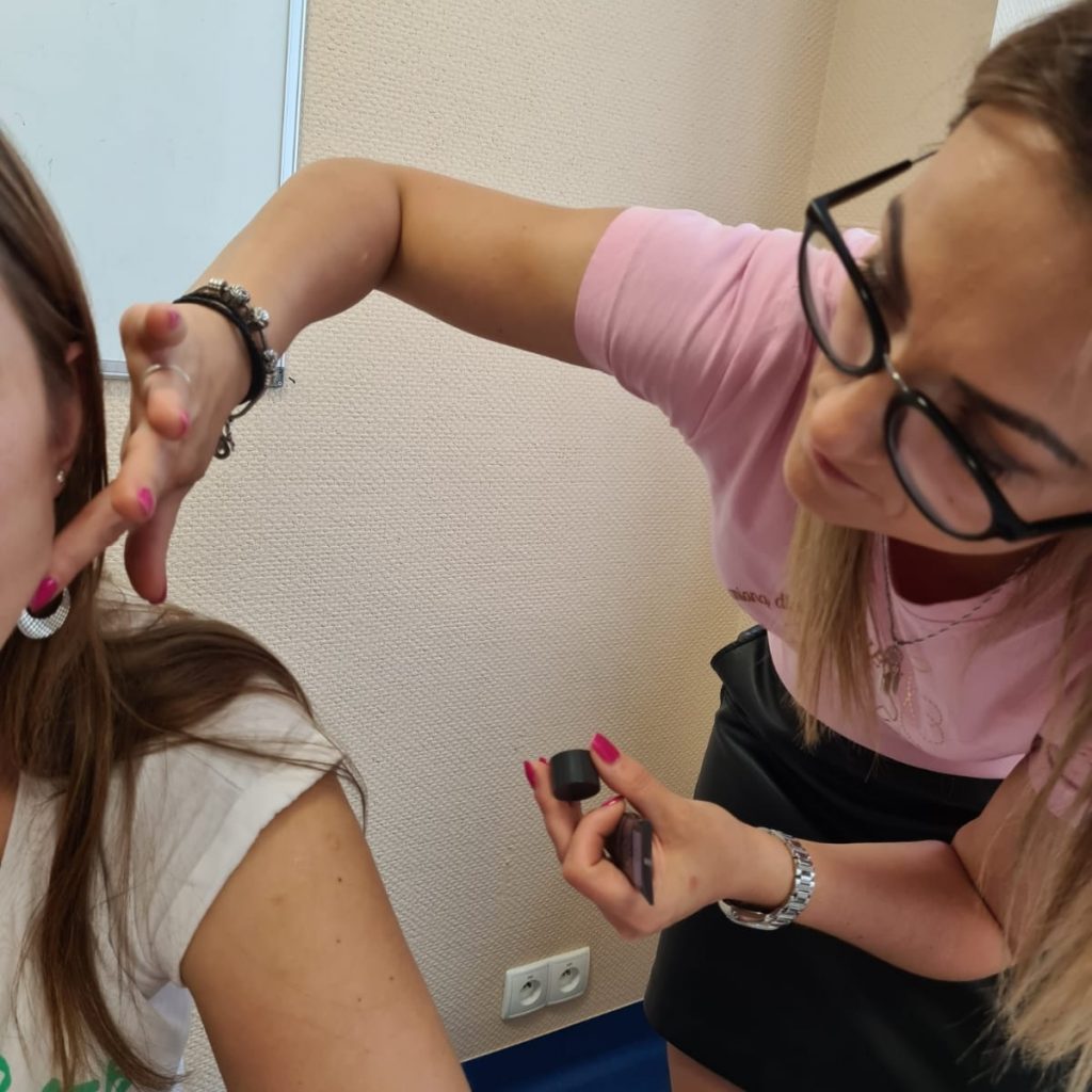 Makijażystka nakłada kosmetyki na twarz klientki, pokazując techniki makijażu.