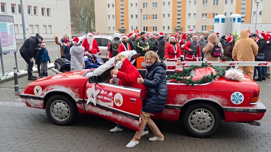 Czerwony kabriolet Motomikołaja udekorowany świątecznie na parkingu przy budynkach szpitala