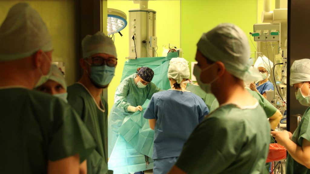 Zespół chirurgiczny w operacyjnej, lekarze w maseczkach i odzieży ochronnej, podczas zabiegu w szpitalu.