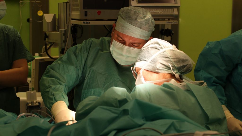 Chirurdzy w zespole przeprowadzają operację, skoncentrowani na precyzyjnych ruchach i technikach.