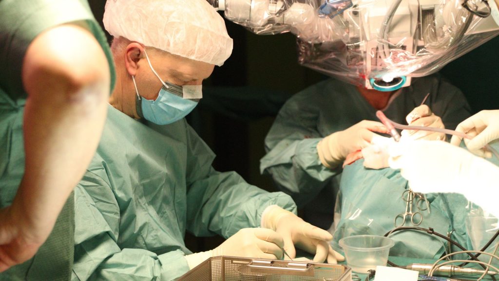 Zespół chirurgiczny pracujący na sali operacyjnej, skupiony na precyzyjnej wykonaniu zabiegu, w pełnym przygotowaniu.