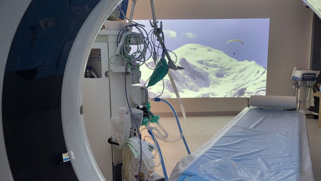 Nowoczesna sala medyczna z tomografem komputerowym, wyposażona w sprzęt oraz panoramiczny widok gór.
