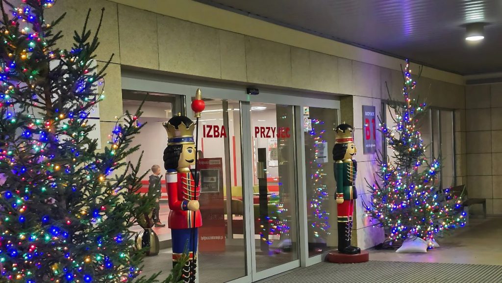 Świąteczna dekoracja przed wejściem do izby przyjęć, z kolorowymi drzewkami i figurkami dziadka do orzechów.