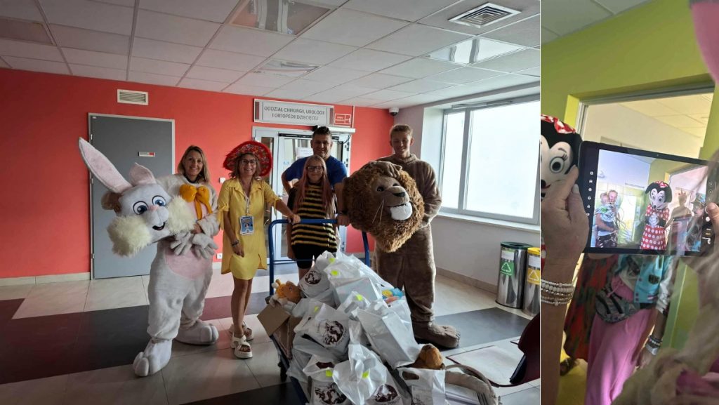 Wolontariusze w kolorowych strojach przed wejściem do oddziału szpitalnego, obok paczki z prezentami dla dzieci